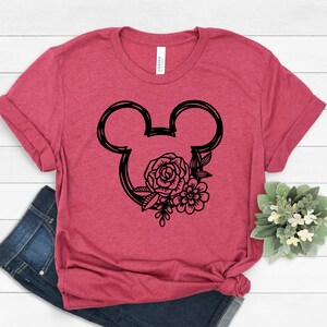May include: A red t-shirt with a black outline of Mickey Mouse ears with floral accents.