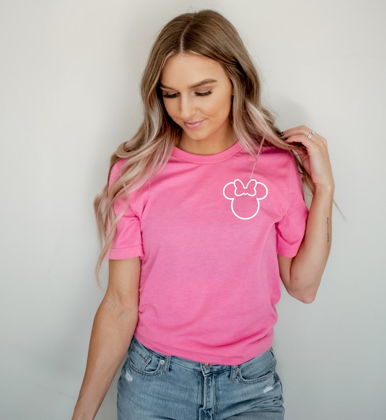 May include: A pink t-shirt with a white outline of Minnie Mouse's head with a bow on top.