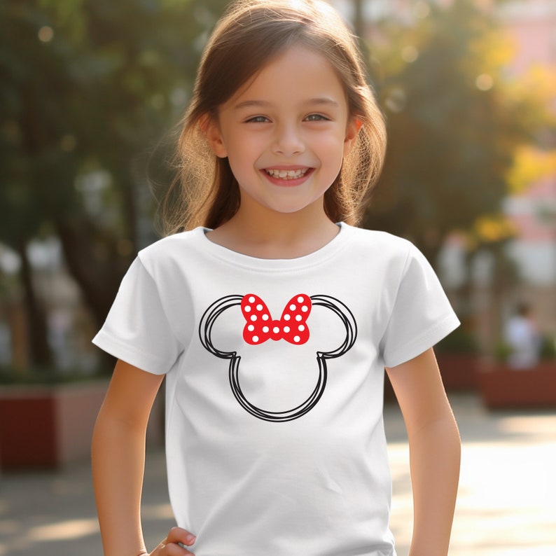 May include: White t-shirt with a black and red Minnie Mouse head graphic. The graphic features a red bow with white polka dots.