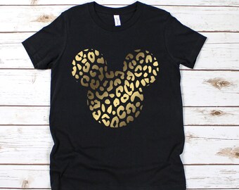 May include: Black t-shirt featuring a gold leopard print Mickey Mouse design. The graphic is centered on the front of the shirt. The shirt is made of a soft material and is suitable for casual wear.