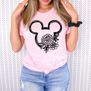May include: A pink t-shirt with a black outline of Mickey Mouse ears with floral designs inside the ears.
