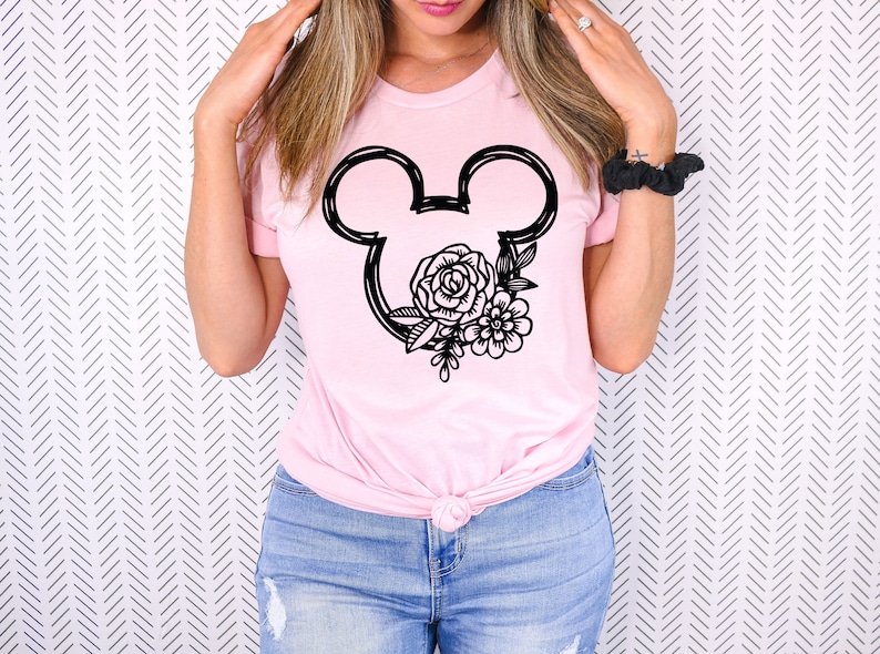 May include: A pink t-shirt with a black outline of Mickey Mouse ears with floral designs inside the ears.