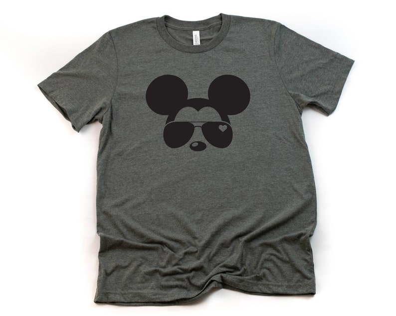 Op de afbeelding: Een donkergrijs T-shirt met een zwart-witte afbeelding van Mickey Mouse met een zonnebril met een hart op de lens.