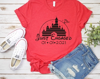May include: Red t-shirt with a black graphic of Cinderella's castle and the text "Just Engaged 01 01 2021".