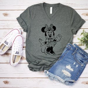 May include: A dark gray V-neck t-shirt with a black and white graphic of Minnie Mouse. The graphic shows Minnie Mouse wearing a polka dot dress and a bow.