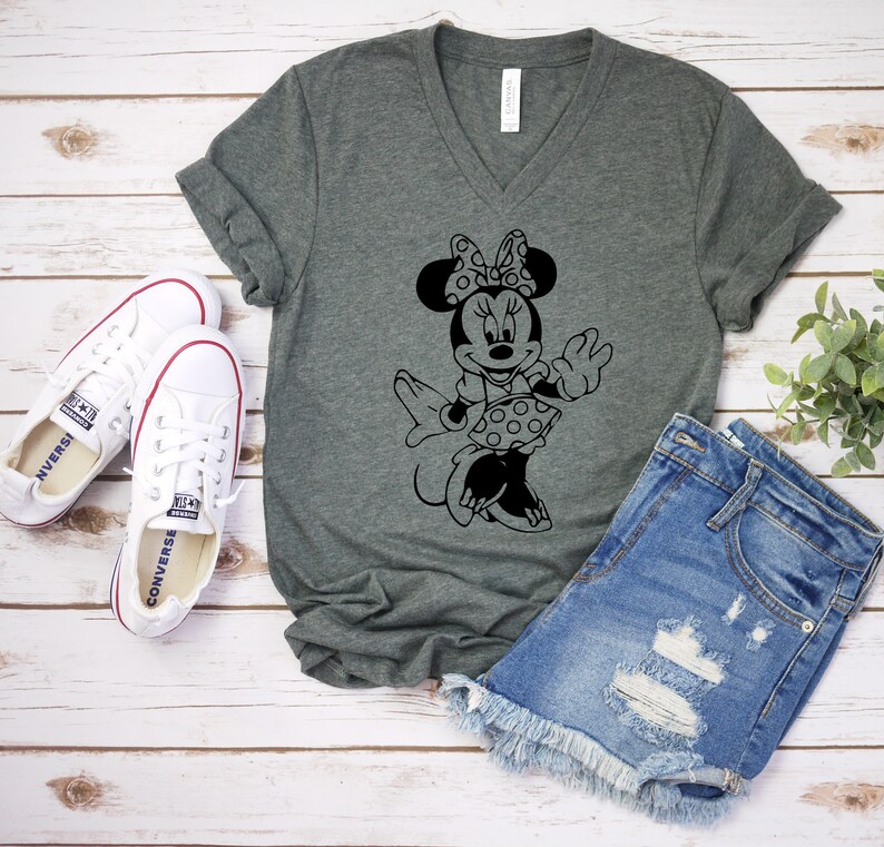 May include: A dark gray V-neck t-shirt with a black and white graphic of Minnie Mouse. The graphic shows Minnie Mouse wearing a polka dot dress and a bow.