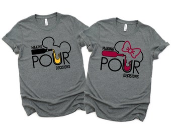 May include: Two gray t-shirts with a black and yellow graphic on one and a black, red, and yellow graphic on the other. The text on both shirts reads "Making Pour Decisions".