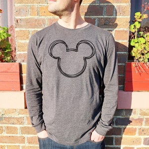 Op de afbeelding: Een donkergrijs shirt met lange mouwen met een zwarte omtrek van Mickey Mouse's hoofd op de voorkant.
