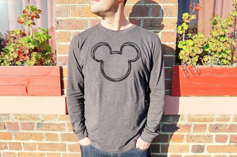 Op de afbeelding: Een donkergrijs shirt met lange mouwen met een zwarte omtrek van Mickey Mouse's hoofd op de voorkant.