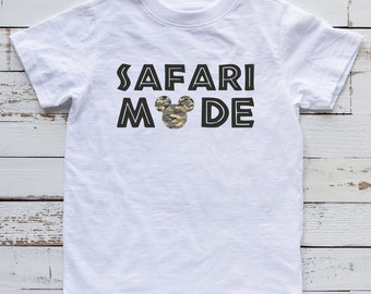 May include: White t-shirt with black text that reads "Safari Mode" with a camouflage Mickey Mouse head in the middle of the text.