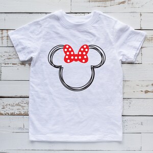 May include: White t-shirt with a black and white outline of Mickey Mouse's head with a red bow with white polka dots.