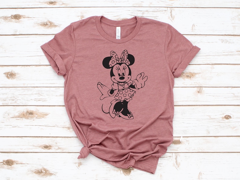 May include: A mauve t-shirt with a black silhouette of Minnie Mouse wearing a polka dot dress and a bow.