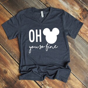 Może przedstawiać: Szary T-shirt z dekoltem w kształcie litery V z białym nadrukiem uszu Myszki Miki i tekstem "OH you so fine".