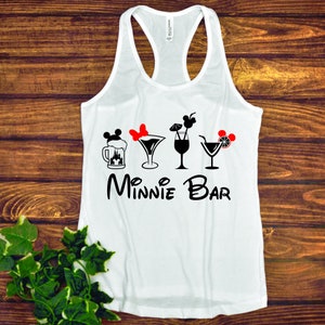May include: White tank top with a black graphic of Mickey Mouse ears, a red bow, a beer mug with a castle, a martini glass, a wine glass, and a cocktail glass with a lime wedge. The text "Minnie Bar" is below the graphic.