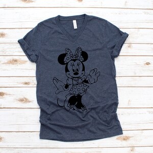 May include: A dark blue V-neck t-shirt with a black and white silhouette of Minnie Mouse wearing a polka dot dress and a bow.
