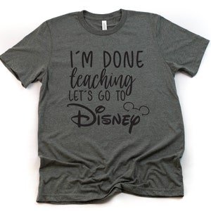 May include: A dark gray t-shirt with the text "I'm done teaching let's go to Disney" in black lettering. The text includes a Mickey Mouse head icon.