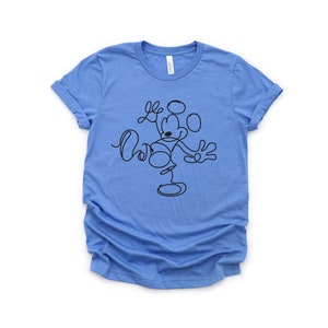Puede incluir: Una camiseta azul claro con un dibujo de l&iacute;nea negra de Mickey Mouse. El dibujo es estilizado y muestra a Mickey Mouse saludando con los brazos extendidos.