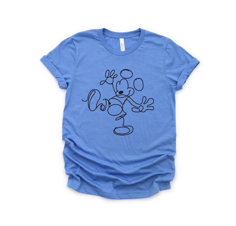 Puede incluir: Una camiseta azul claro con un dibujo de l&iacute;nea negra de Mickey Mouse. El dibujo es estilizado y muestra a Mickey Mouse saludando con los brazos extendidos.