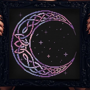 May include: A framed cross-stitch featuring a crescent moon design with Celtic knotwork and stars. The moon is rendered in shades of purple and blue against a black background. The frame is black and ornate, adding a touch of elegance to the artwork.