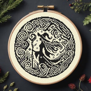 Könnte beinhalten: Schwarzweißes Kreuzstichmuster einer Hexe mit einem Zauberstab, umgeben von wirbelnden Designs. Das Muster befindet sich in einem runden Reifen.