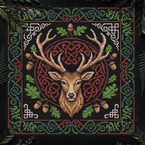 Puede incluir: Un diseño de punto de cruz que presenta un ciervo detallado con grandes astas, centrado dentro de un diseño de nudo celta. La obra de arte incorpora colores rojo, verde y marrón sobre un fondo negro, rodeado por un borde decorativo con bellotas y hojas.