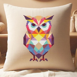 May include: A decorative pillow with a geometric owl design. The owl is composed of colorful, angular shapes in shades of pink, orange, yellow, blue, and purple. The pillow has a neutral, beige background.