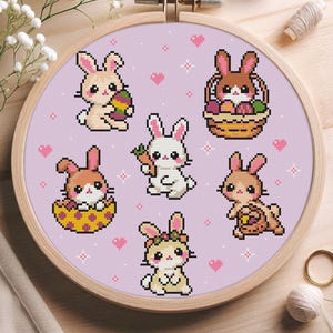 Könnte beinhalten: Ein Kreuzstich-Stickrahmen mit sechs entzückenden pixeligen Hasen. Die Hasen sind in Braun-, Weiß- und Beigetönen gehalten und halten Ostereier, Karotten und Körbe. Der Hintergrund ist hellviolett mit Herzen und Kreuzstichdetails.
