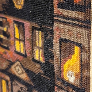 The image is a close-up of a colorful, textured tapestry or textile featuring a variety of patterns and designs, including a building with a clock and a yellow object.
