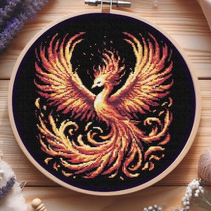 Könnte beinhalten: Kreuzstich-Stickerei eines Phönix in einem Holzreifen. Der Vogel ist mit feurigen Orange-, Gelb- und Rottönen vor einem schwarzen Hintergrund dargestellt. Der Phönix hat ausgebreitete Flügel und einen fließenden Schwanz, was ein dynamisches und detailliertes Design ergibt.
