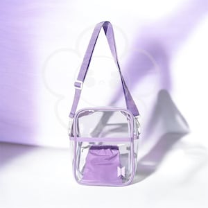 Peut inclure: Un sac bandouli&egrave;re carr&eacute; transparent avec une sangle et des bordures lilas. Le sac contient une petite pochette &agrave; cordon de serrage lilas et un logo blanc &agrave; l'avant. Le fond est lilas clair avec un motif floral.