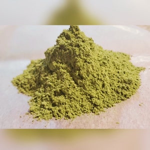 Peut inclure: Un tas de poudre verte, probablement une épice ou une herbe, sur une surface blanche.