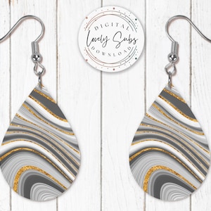 May include: A pair of silver teardrop-shaped earrings with a gray, white, and gold abstract swirl pattern.