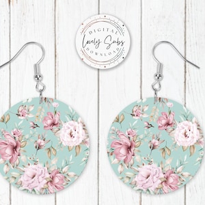 May include: A pair of round, light blue earrings with a floral pattern featuring pink and white flowers. The earrings have silver hooks.