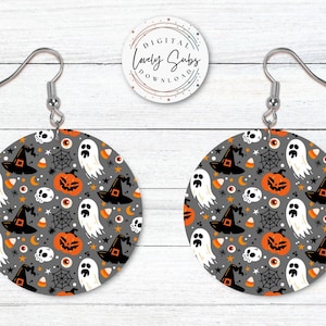 May include: A pair of Halloween-themed earrings. Each earring is a gray circle with a repeating pattern of orange pumpkins, witch hats, ghosts, spiderwebs, and candy corn. The earrings have silver-colored fish hook ear wires. The text "DIGITAL LOVELY SUBS" is in a circle in the background.