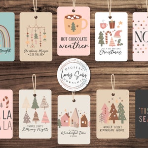 Puede incluir: Una colección de etiquetas de regalo con temática navideña con varios diseños y texto. Las etiquetas presentan ilustraciones de un arcoíris, árboles de Navidad, casas y frases festivas como "Merry & Bright" y "Noel". Cada etiqueta es rectangular con una cuerda.
