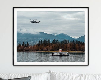 May include: A framed photograph of a helicopter flying over a body of water with mountains in the background. The water is calm and the sky is cloudy.
