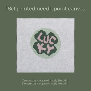 May include: Printed needlepoint canvas with a four-leaf clover design. The clover is green with the word "LUCKY" in pink. The canvas size is approximately 8in x 8in, and the design size is approximately 4in x 4in.
