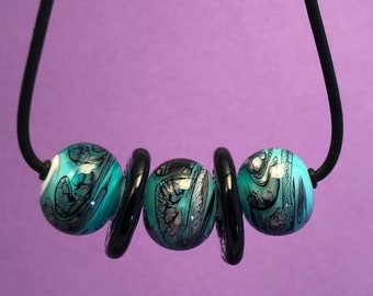 Necklace, Handcrafted Glass Beads, 18", 3 teal and black beads with 2 black disks, black rubber cord, sterling silver toggle clasp