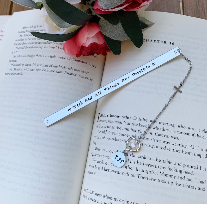 Pu&ograve; includere: Segnalibro d'argento con un cuore e il testo "With God All Things Are Possible" su sfondo bianco. Il segnalibro &egrave; attaccato a una catena d'argento con un ciondolo a forma di croce.