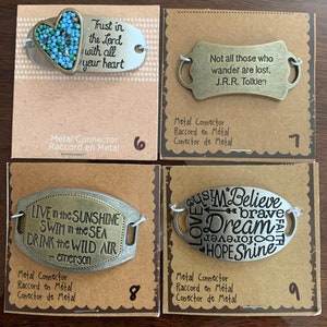 May include: Four metal charm tags with inspirational quotes and sayings. The charms are silver and gold in color and have a heart, a sun, and a star design. The charms are labeled with numbers 6, 7, 8, and 9.