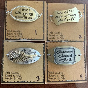 May include: Four metal charm bracelets with inspirational quotes. The charms are oval shaped and feature a gold or silver finish. The charms are numbered 1 through 4. The charms feature the following quotes: "She leaves a little sparkle wherever she goes", "What if I fall? Oh, but my Darling... what if you fly?", "With brave wings she flies...", and "She believed she could so she did".