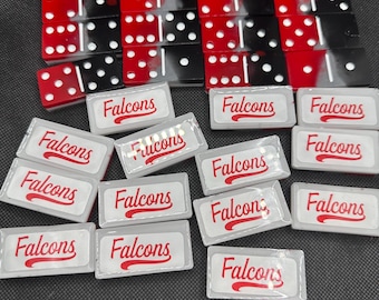 May include: A collection of dominoes and small rectangular boxes. The dominoes are red and black with white dots. The boxes are white with the word "Falcons" in red script.