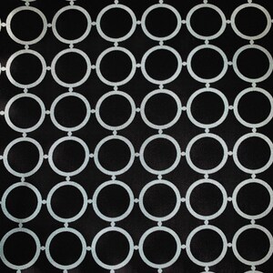 May include: Black fabric with a repeating pattern of white circles. The circles are connected to each other, creating a chain-like design.