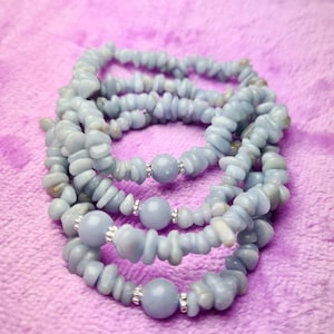 May include: A set of four blue gemstone bracelets with silver beads. The bracelets are made of small, irregular shaped stones and are stacked on top of each other.