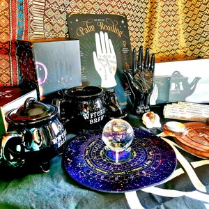 以下が含まれることがあります： 黒の釜型のマグカップ、蓋付きの黒の釜、スタンドに乗ったクリスタルボール、キャンドルが置かれた木製のトレイ、手のひらを読む本、黒い手の置物など、魔女をテーマにしたアイテムのコレクションです。