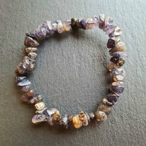 May include: A purple and brown gemstone bracelet made of small, irregular shaped stones.