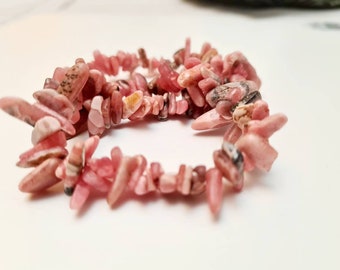 May include: A pink and white gemstone bracelet made of small, irregular shaped stones.