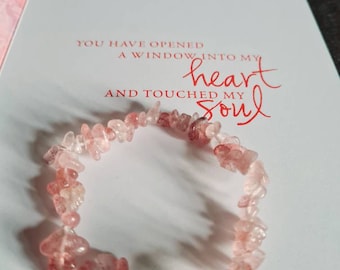May include: A pink and clear crystal bracelet with a large pink crystal bead. The bracelet is on a white background with the text "You have opened a window into my heart and touched my soul".