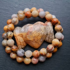 May include: A double-strand bracelet made of brown, white and orange agate beads. The beads are round and have a natural, polished finish.