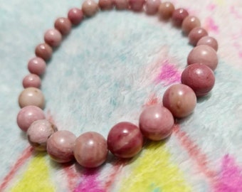 May include: A pink gemstone bracelet with round beads. The bracelet is made of natural stones and is a beautiful accessory for any occasion.